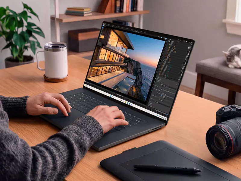 XPS 16 Creator Edition บนโต๊ะทำงาน หน้าจอเปิดโปรแกรมงานภาพสามมิติ ข้างกล้องและแท็บเล็ตวาดภาพ