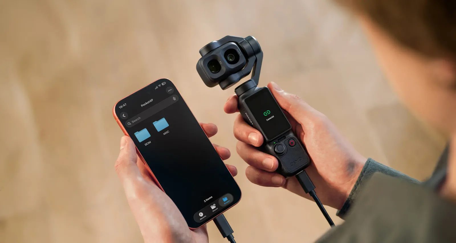 ผู้ใช้ถือ Osmo Pocket 4P ต่อสายเข้ากับสมาร์ตโฟนเพื่อถ่ายโอนไฟล์