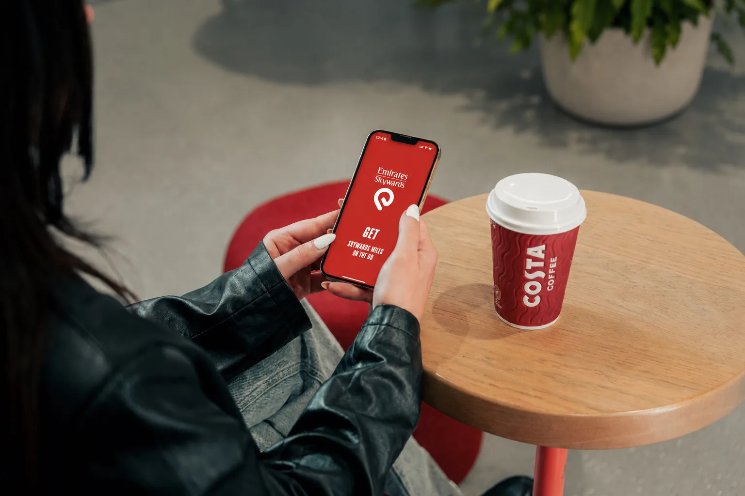 แอป Emirates Skywards บนโทรศัพท์มือถือวางคู่กับแก้วกาแฟ Costa ภาพจาก Emirates สื่อถึงการสะสมไมล์ผ่าน Skywards Everyday