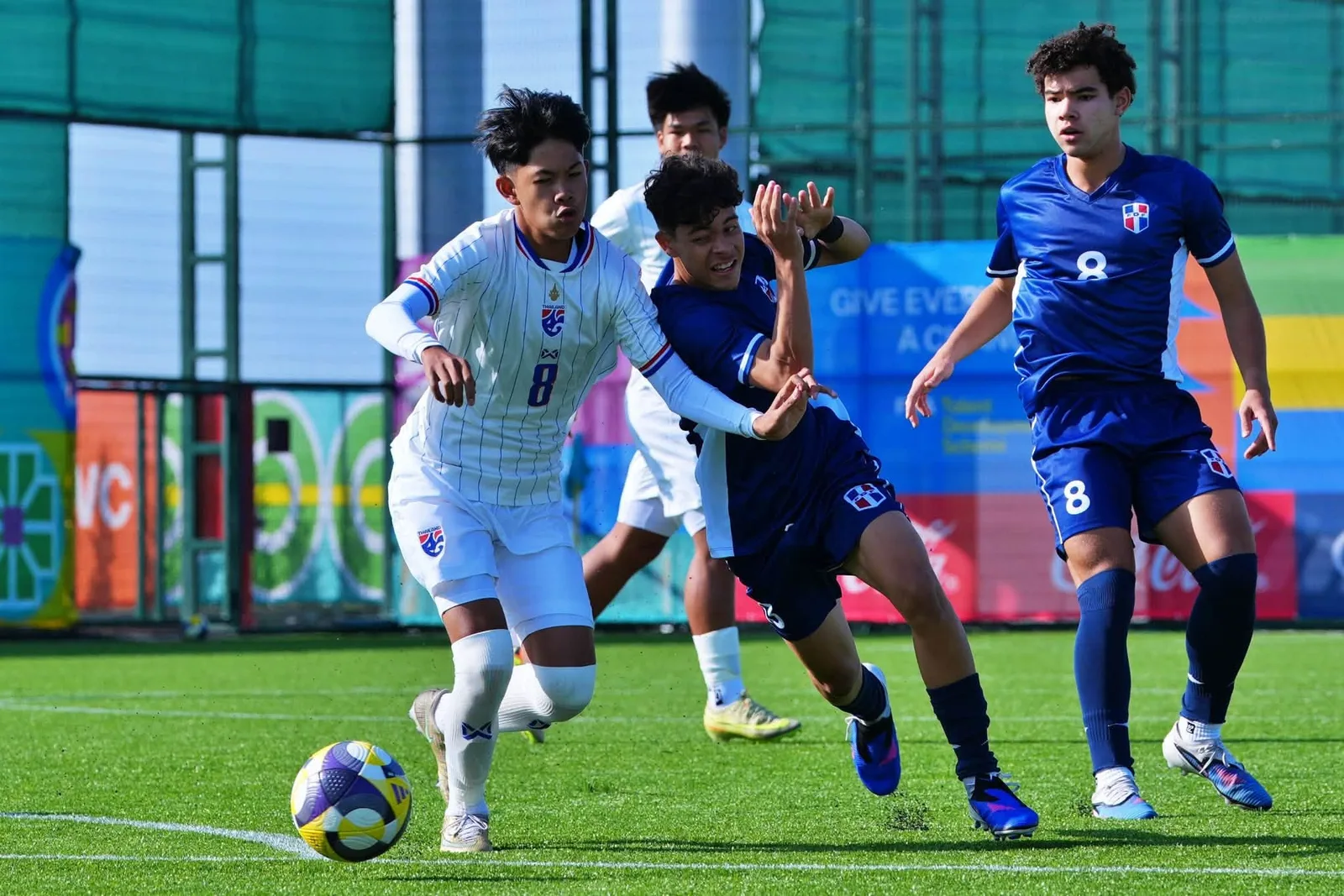 นักเตะทีมชาติไทย U15 หมายเลข 8 ชุดขาว คุมบอลหนีผู้เล่นโดมินิกันชุดน้ำเงิน ในนัดแรกของ FIFA U-15 World Cup 2026 ที่บากู