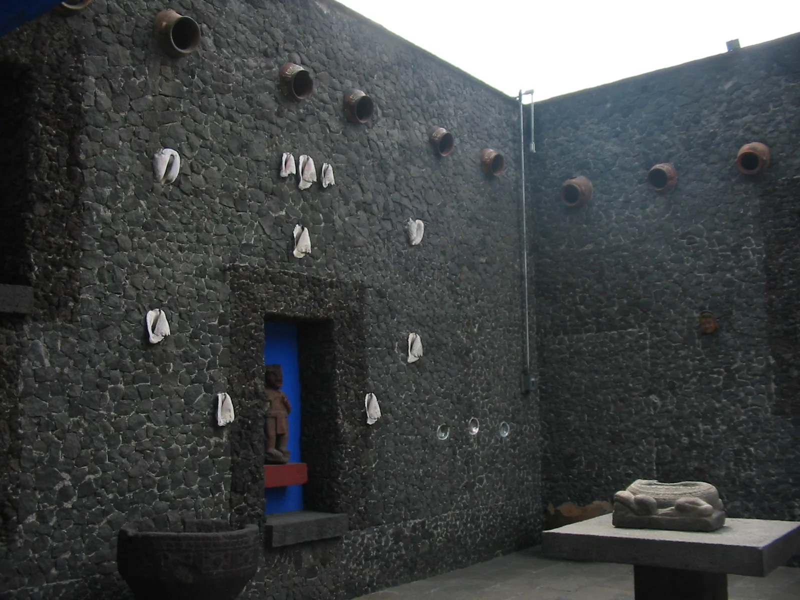 ผนังหินภูเขาไฟในลานด้านในของ Casa Azul ฝังเปลือกหอยและไหดินเผา มีช่องตั้งรูปสลักหิน ภาพถ่ายเดือนมีนาคม 2008