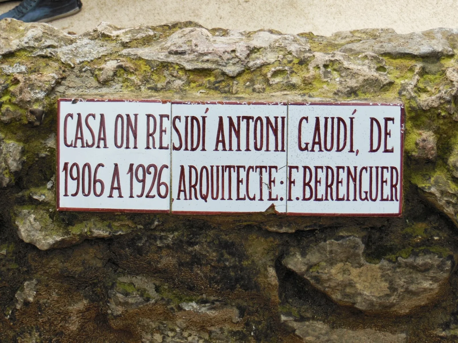 ป้ายกระเบื้องบนกำแพงบ้านเกาดี้ เขียนว่า Gaudí อาศัยที่นี่ปี 1906–1926 และสถาปนิกคือ F. Berenguer
