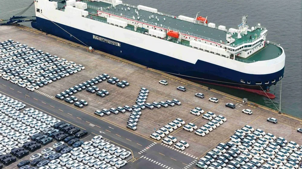 GEELY EX2 จำนวนมากจอดเรียงเป็นตัวอักษร EX2 ที่ท่าเรือข้างเรือขนส่งรถยนต์