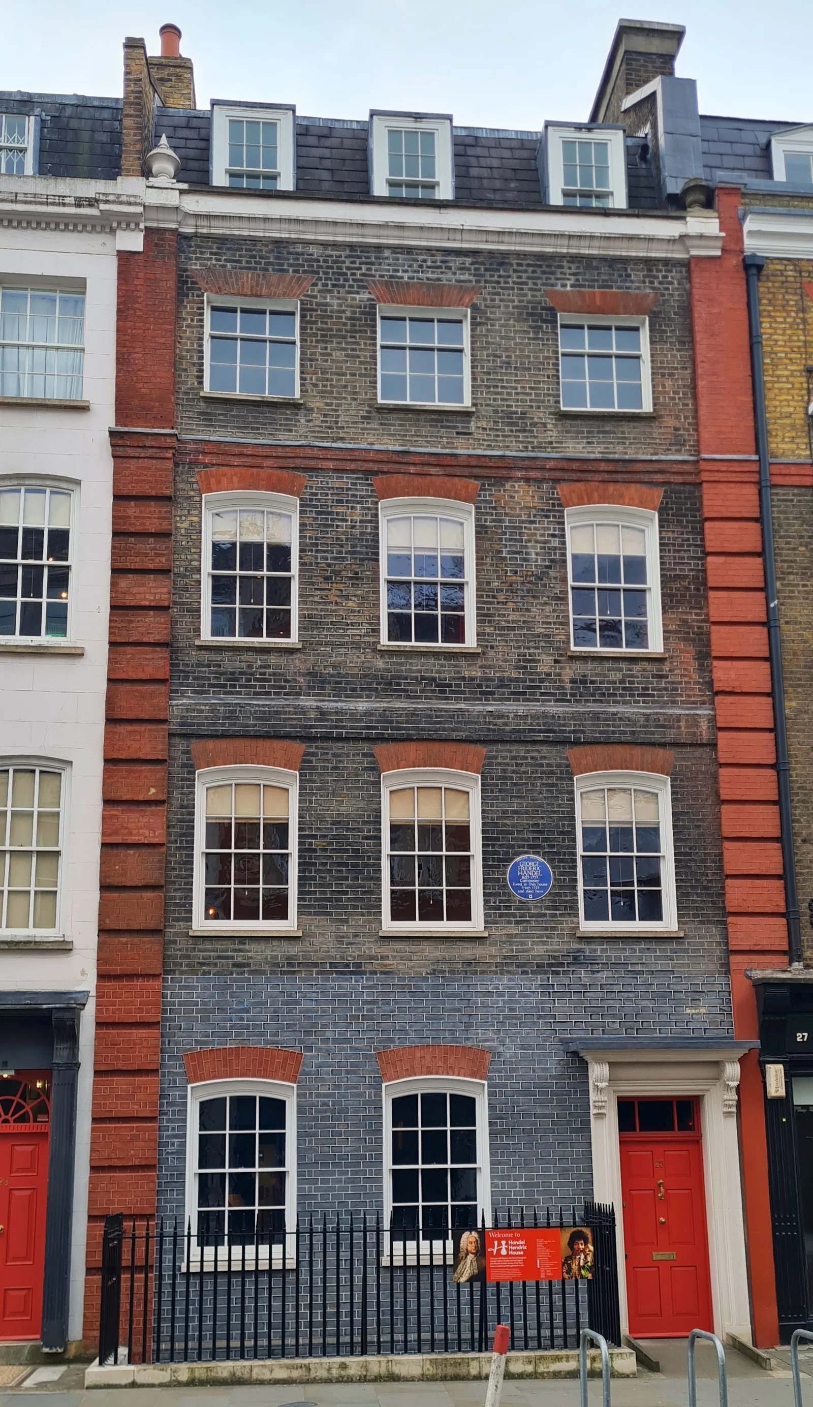 ด้านหน้าอาคารเลขที่ 25 Brook Street ของ Handel Hendrix House ประตูหน้าสีแดง ภาพถ่ายเมื่อ 23 มีนาคม 2025
