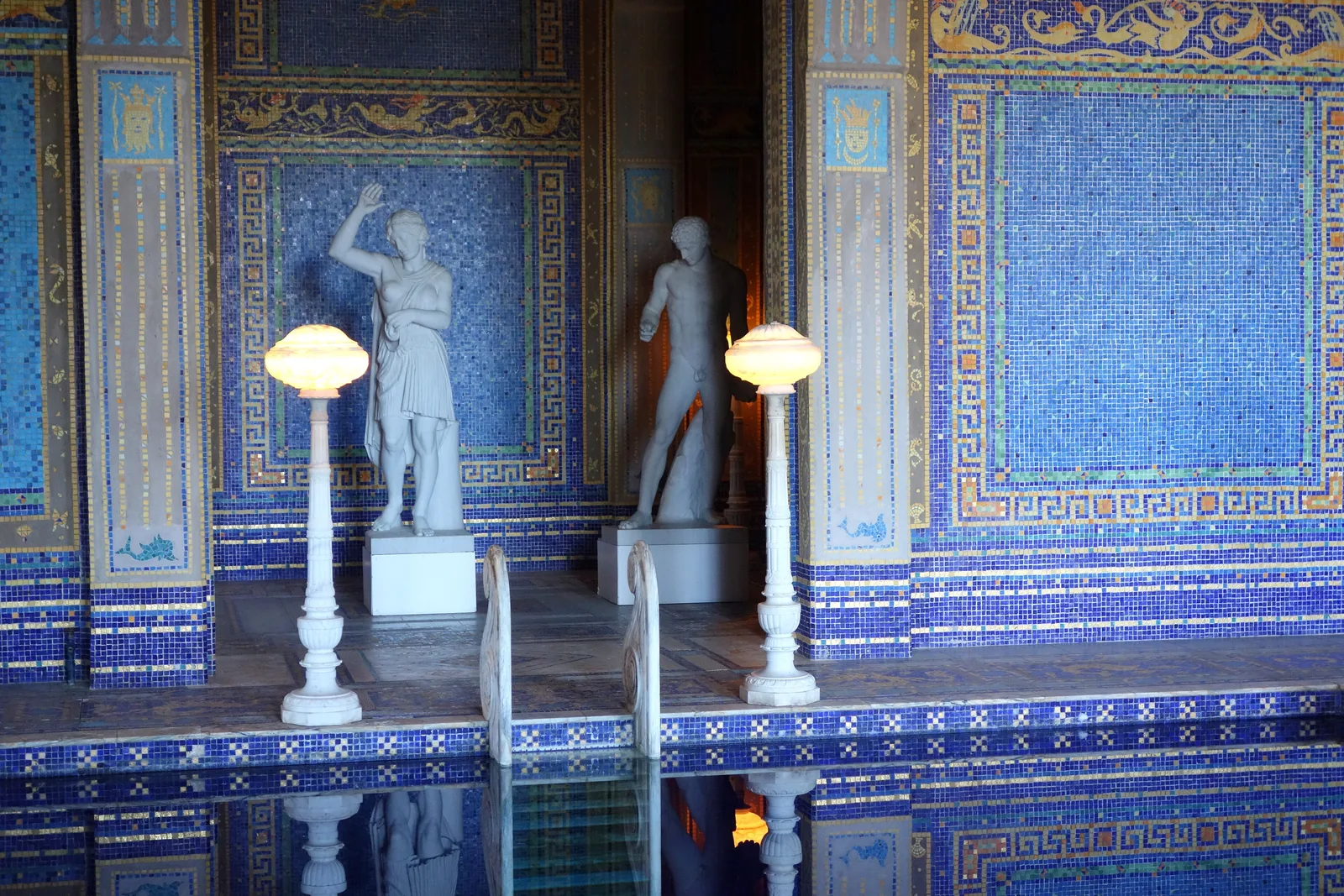 รูปปั้นหินอ่อนและโคมไฟริม Roman Pool สระในร่มของ Hearst Castle ผนังกรุโมเสกสีน้ำเงินลายทอง