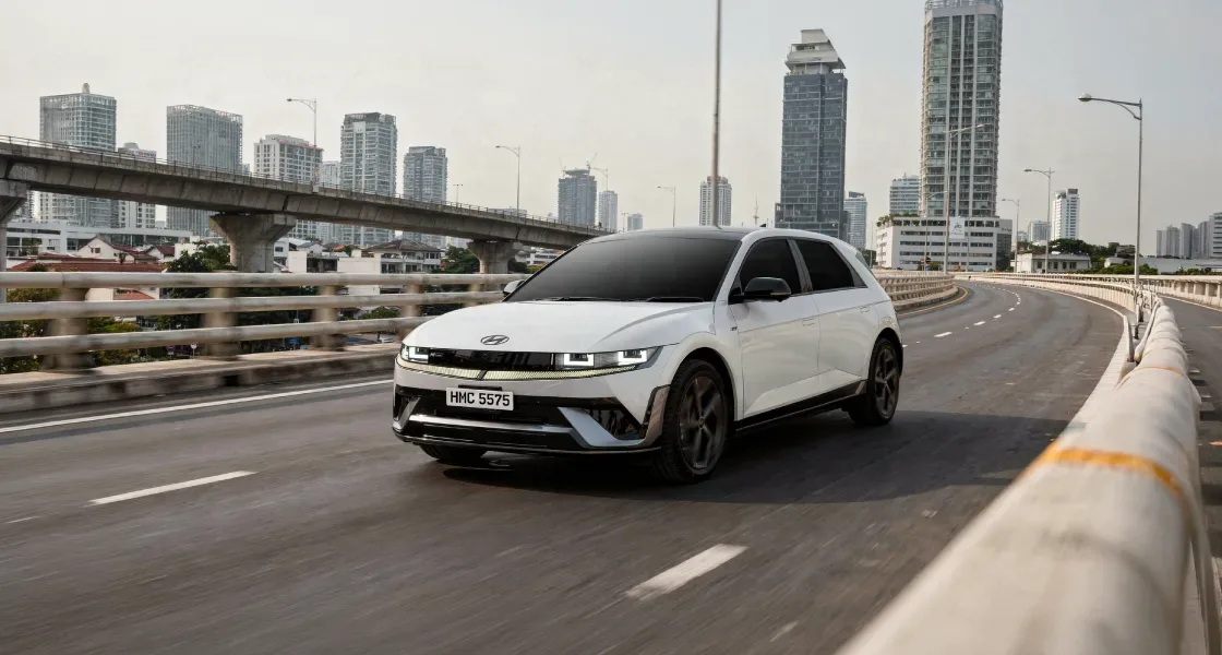 IONIQ 5 N Line สีขาวแล่นบนทางด่วนยกระดับ มีตึกสูงและทางยกระดับอีกเส้นเป็นฉากหลัง