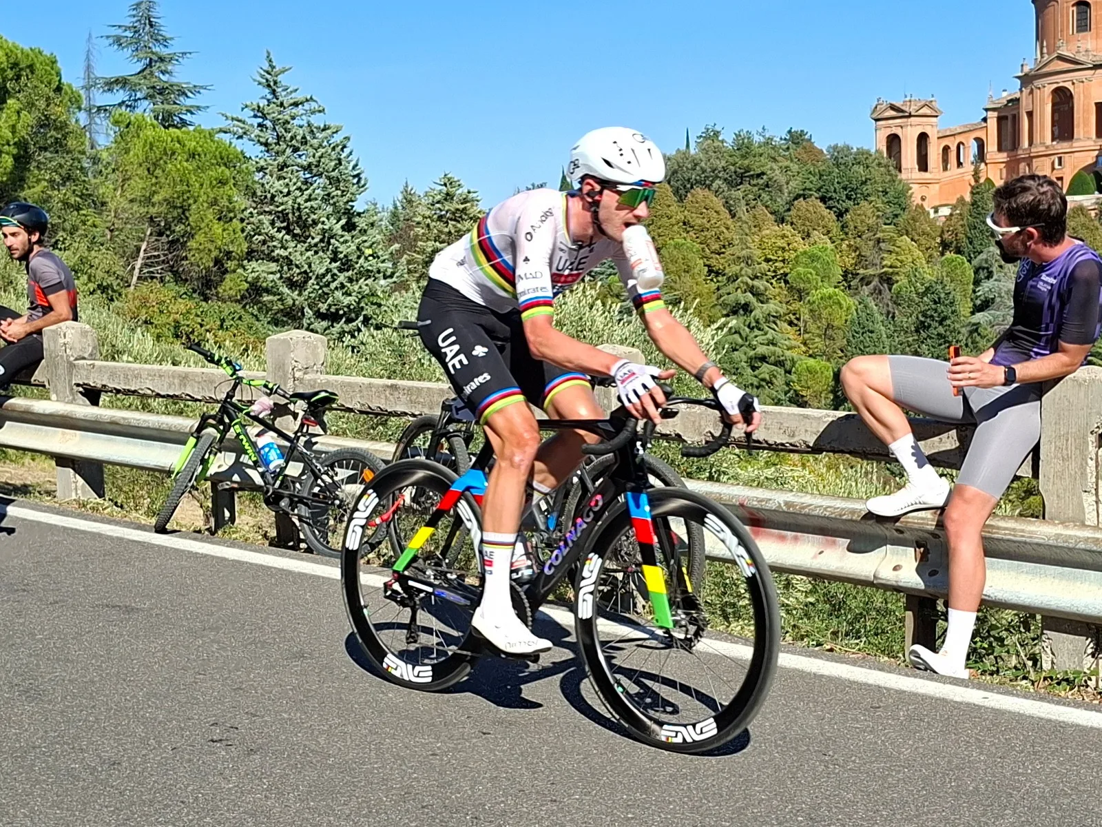 Brandon McNulty แชมป์โลกถนนชาวอเมริกัน ตัวหลักของ UAE Team Emirates XRG ใน Il Lombardia 2026 สวมเสื้อแชมป์โลกลายรุ้ง กางเกงสีดำ หมวกกันน็อกสีขาว แว่นสีเขียว และรองเท้าสีขาว ปั่นจักรยานเสือหมอบเฟรม Colnago สีดำแถบสีรุ้ง ล้อขอบสูงสีดำ ที่ Giro dell'Emilia 3 ตุลาคม 2026