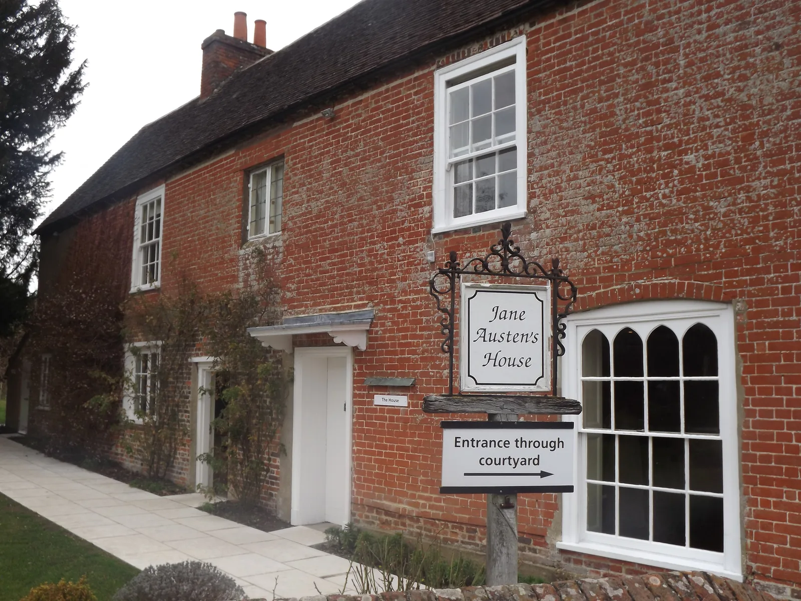 ป้ายบอกทางเข้าผ่านลานด้านข้างหน้าบ้านของ Jane Austen ภาพถ่ายเมื่อ 24 กุมภาพันธ์ 2012