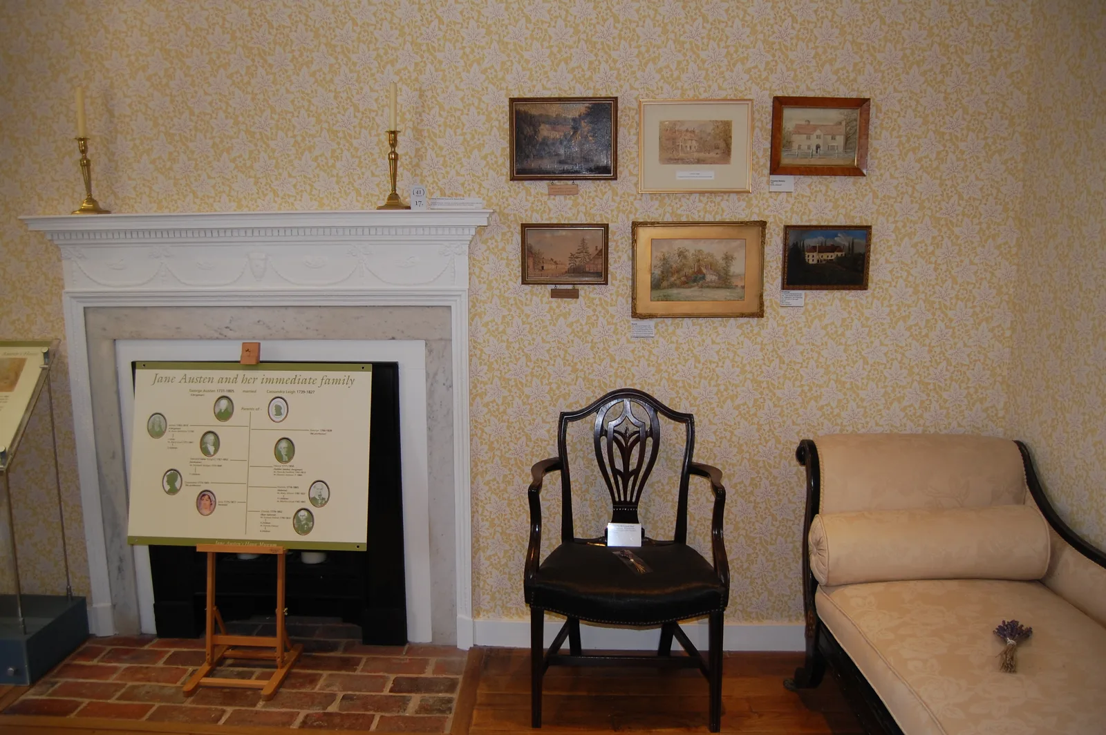 ห้องที่มีเตาผิง เก้าอี้ และภาพแขวนผนังภายในบ้านของ Jane Austen ภาพถ่ายเมื่อ 9 กรกฎาคม 2017