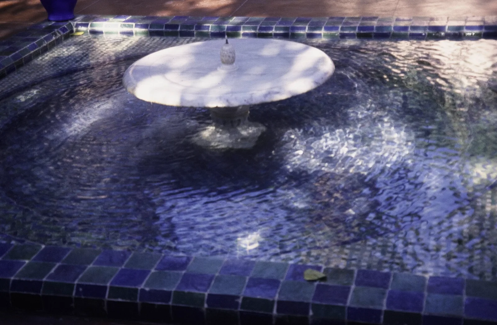 น้ำพุในอ่างสี่เหลี่ยมปูโมเสกสีน้ำเงินใน Jardin Majorelle ภาพจากทศวรรษ 1990