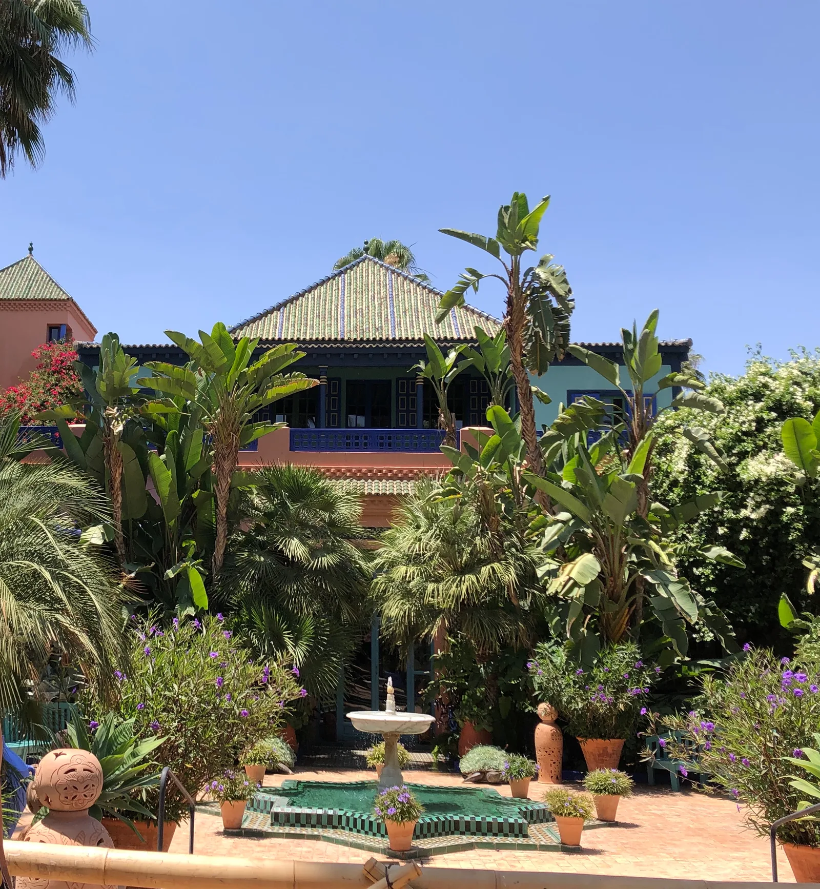 Villa Oasis อดีต Villa Bou Saf Saf ของ Jacques Majorelle หลังคากระเบื้องเขียว มองผ่านสวนไม้เขตร้อนและลานน้ำพุ