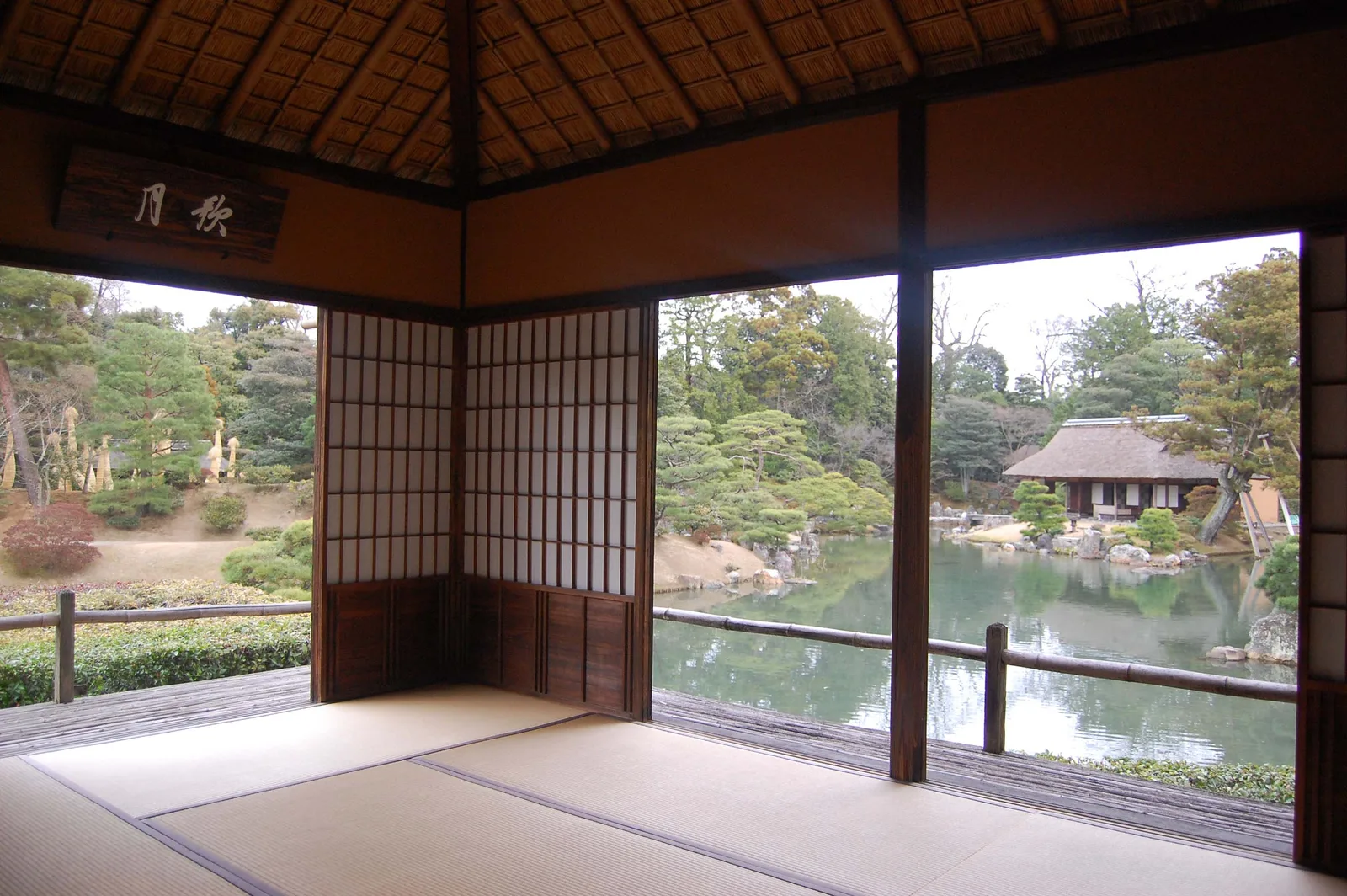 ภายในศาลา Gepparō ในพระตำหนักคัตสึระ มองผ่านช่องเปิดเห็นสระน้ำและโรงน้ำชาหลังคามุงจาก ภาพถ่ายปี 2007