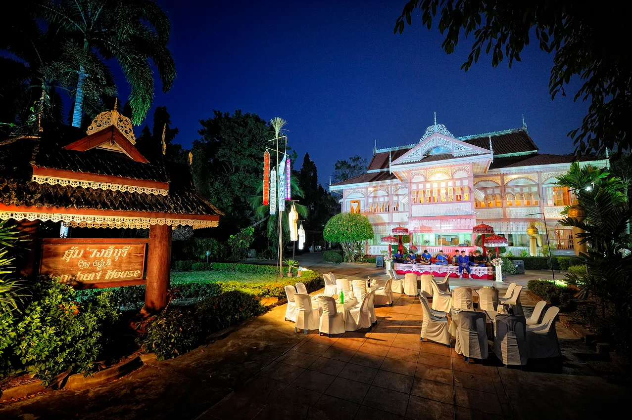 ลานหน้าคุ้มวงศ์บุรียามค่ำ ตัวเรือนเปิดไฟ วงดนตรีเล่นหน้าบ้าน โต๊ะเก้าอี้คลุมผ้าขาว และป้ายไม้ชื่อ The Vongburi House ภาพถ่ายเดือนมกราคม 2014