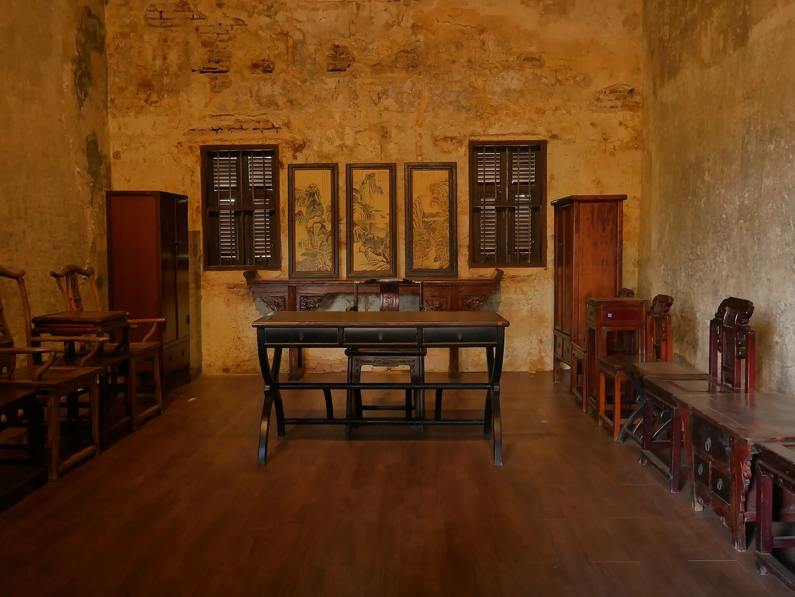 ห้องที่มีโต๊ะไม้กลางห้องและภาพเขียนแบบจีนบนผนัง ในล้ง 1919