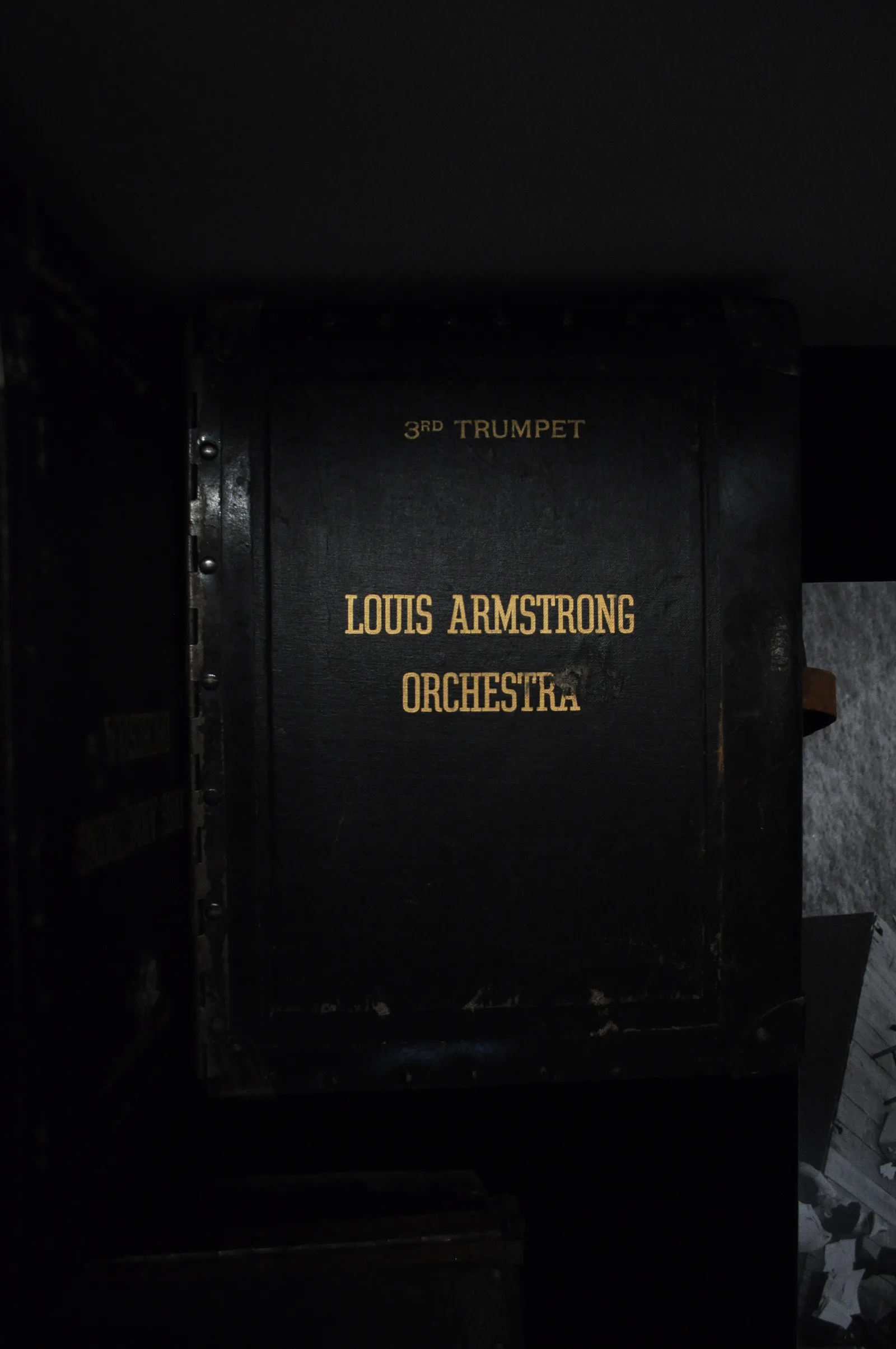 กล่องเก็บโน้ตเพลงสีดำของวง Louis Armstrong Orchestra มีตัวอักษรสีทองระบุตำแหน่ง 3rd Trumpet จัดแสดงในพิพิธภัณฑ์บ้านหลุยส์ อาร์มสตรอง
