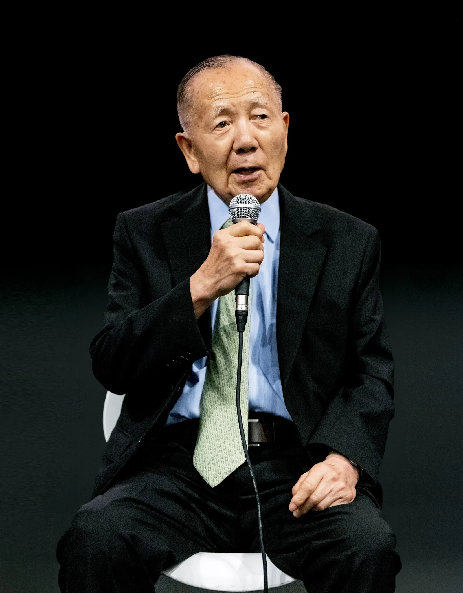 Kim Dong-ho อดีตประธาน BIFF นั่งพูดผ่านไมโครโฟนบนเวทีพื้นหลังสีดำ