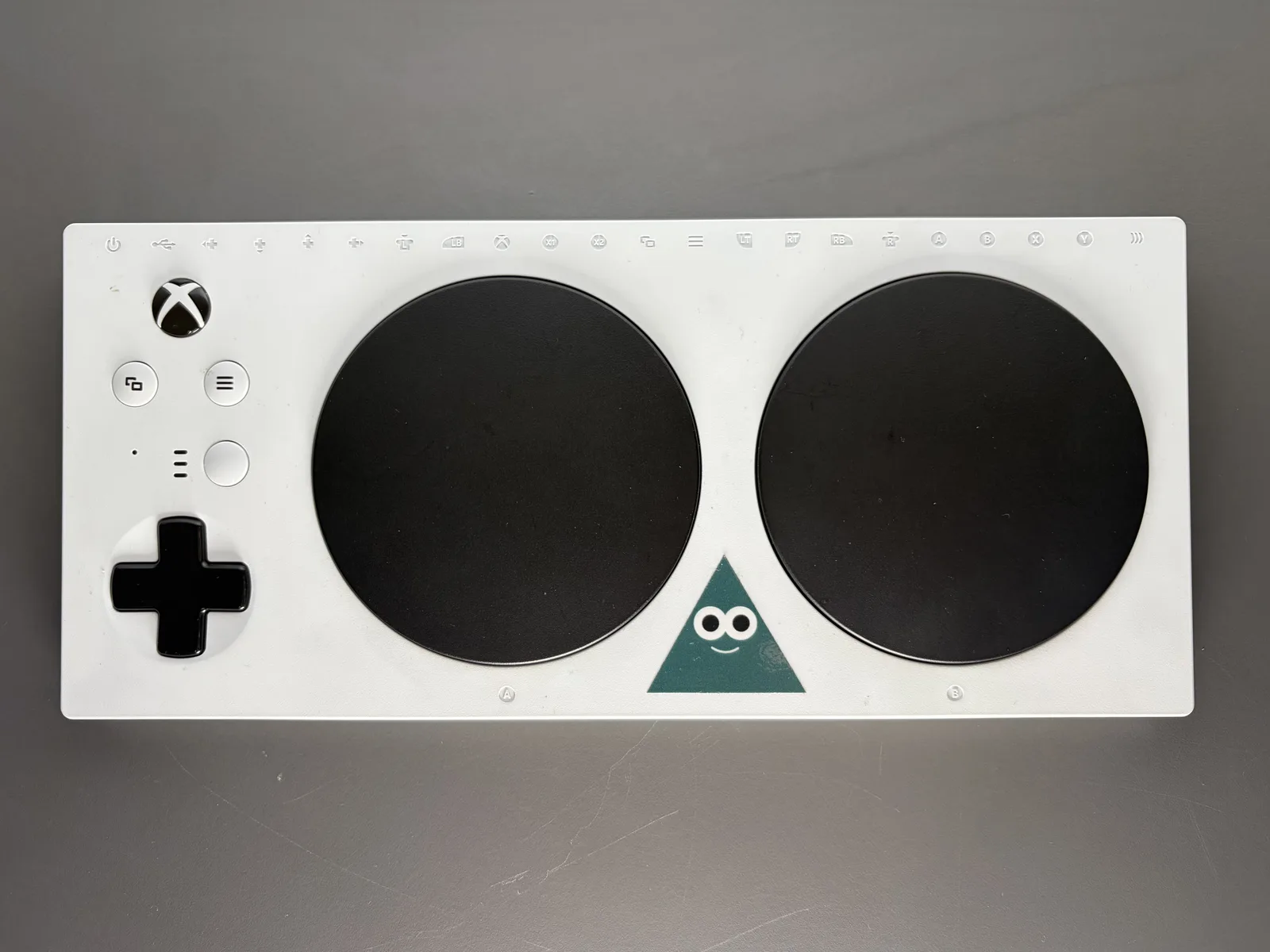 Xbox Adaptive Controller สีขาว ปุ่มกลมขนาดใหญ่สองปุ่มและปุ่มทิศทาง ผลงานที่ถูกพัฒนาต่อในแฮกกาธอนก่อน Microsoft ปิด The Garage