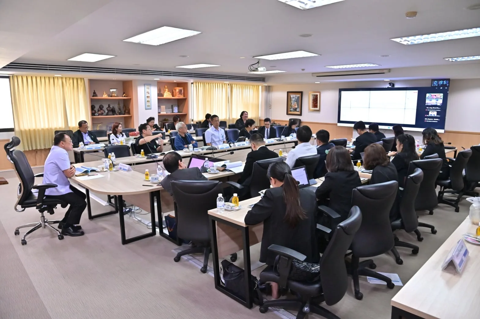 ห้องประชุมของสำนักงานปลัดกระทรวงสาธารณสุขระหว่างการพิจารณางบปฐมภูมิ 2570 คณะอนุกรรมการนั่งรอบโต๊ะประชุมรูปตัวยู มีจอแสดงผู้ร่วมประชุมออนไลน์ที่ผนัง