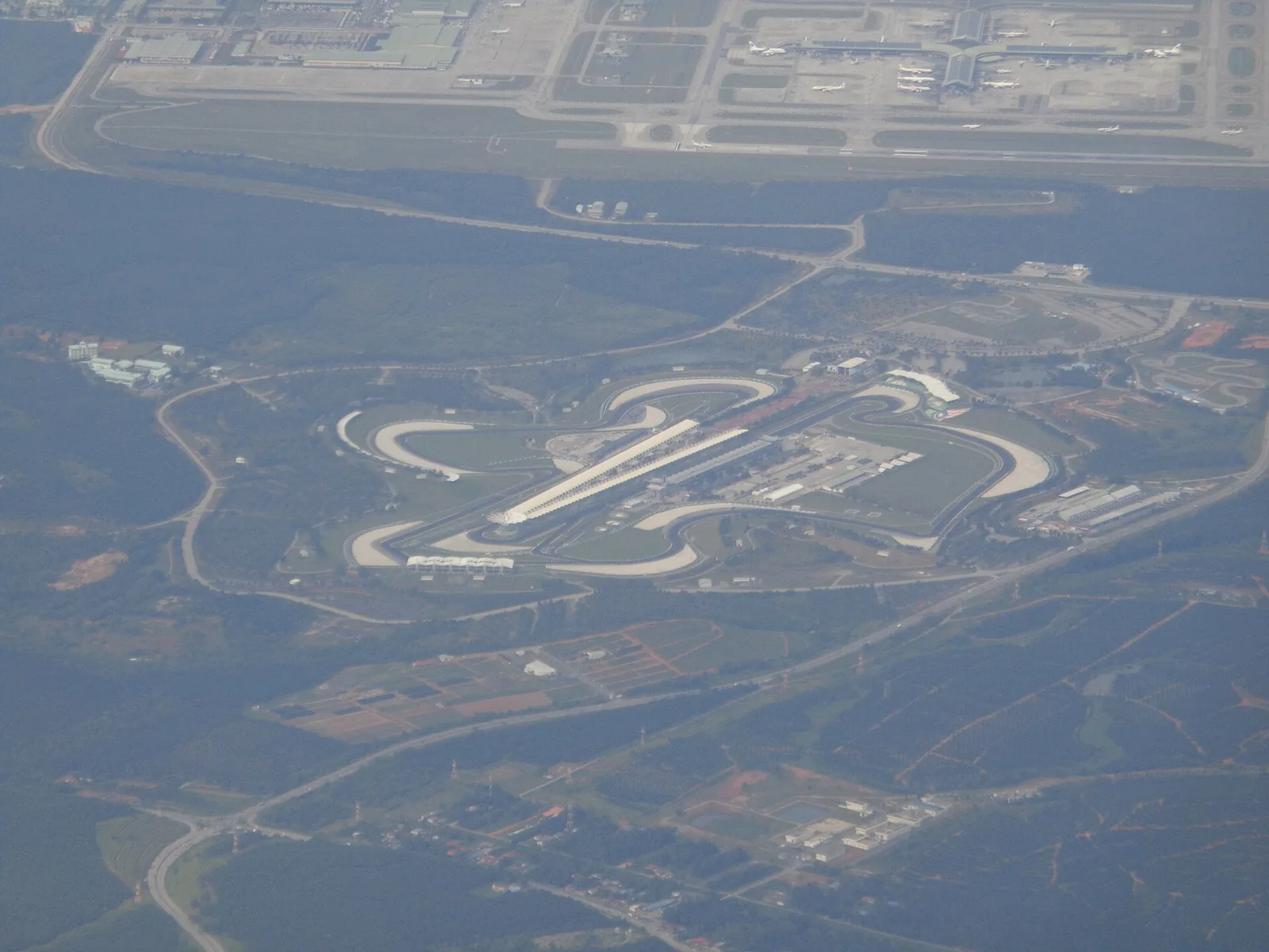 ภาพมุมสูงของสนาม Sepang International Circuit จากเครื่องบิน มีท่าอากาศยานนานาชาติกัวลาลัมเปอร์อยู่ด้านบนของภาพ