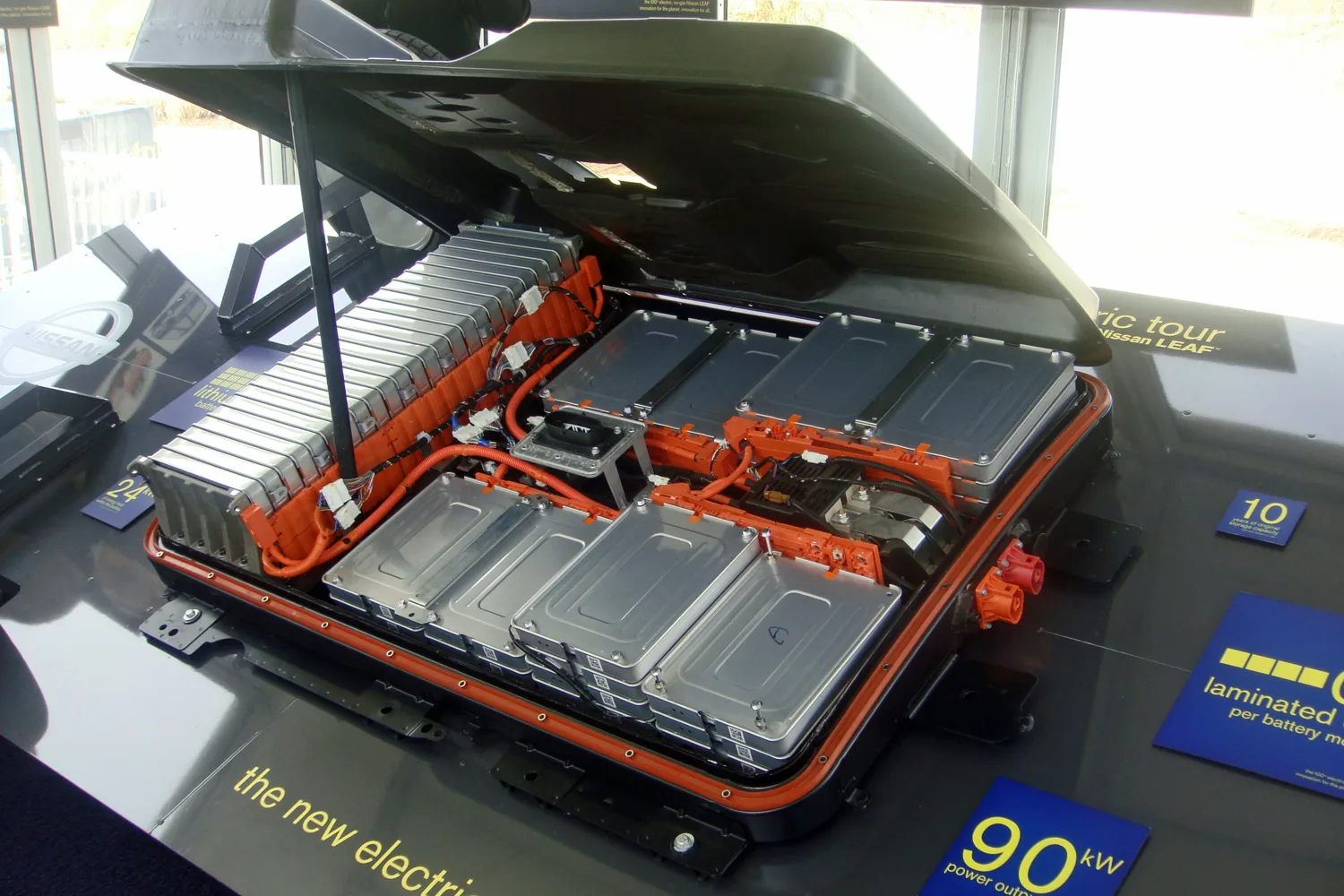 แพ็กแบตเตอรี่ของ Nissan LEAF รุ่นแรกเปิดฝาจัดแสดง เห็นโมดูลเซลล์สีเงินและสายไฟแรงสูงสีส้ม