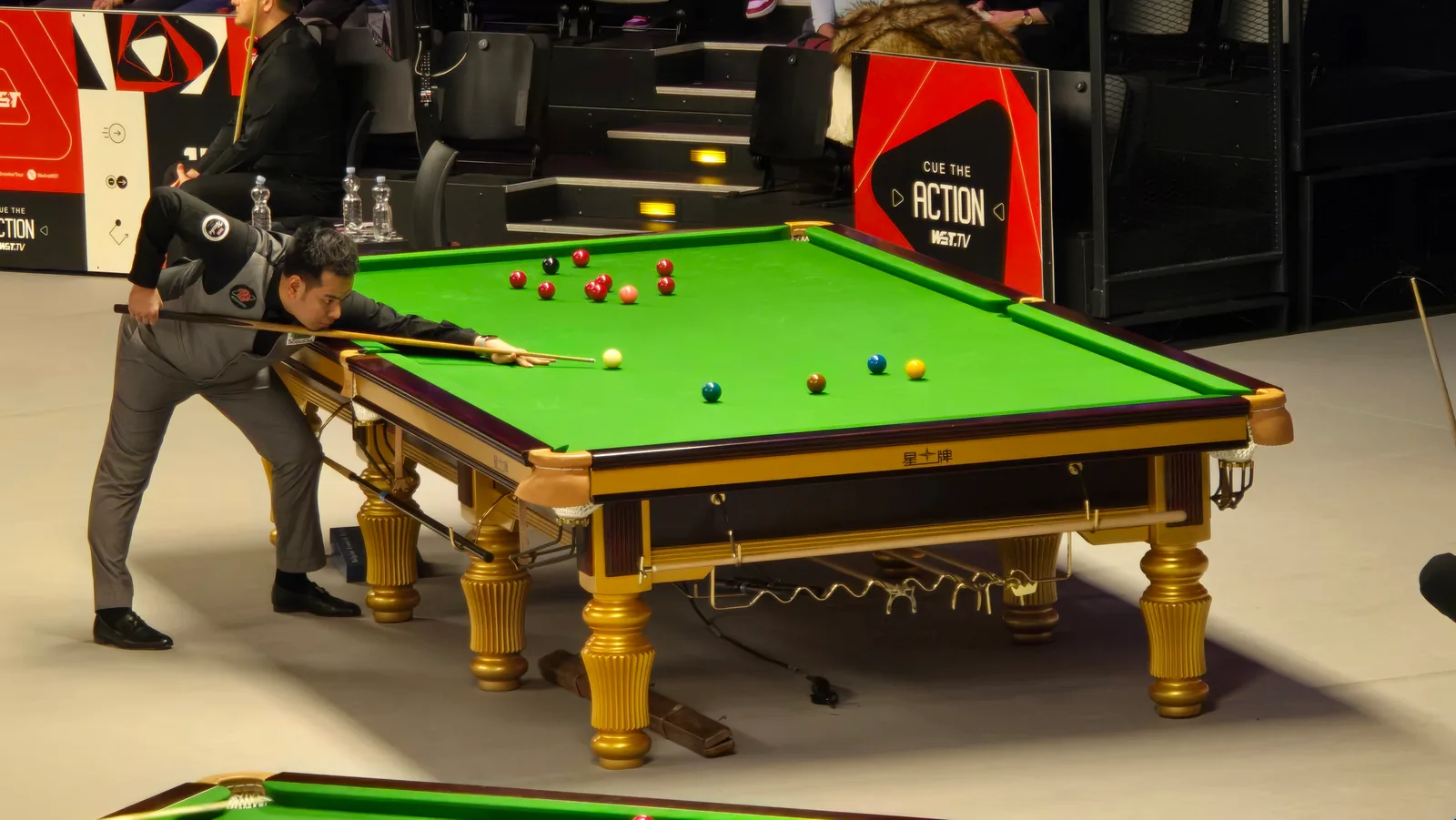 นพพล แสงคำ ในชุดแข่งสีเทา โน้มตัวแทงลูกที่โต๊ะสนุกเกอร์ในรายการ German Masters 2025