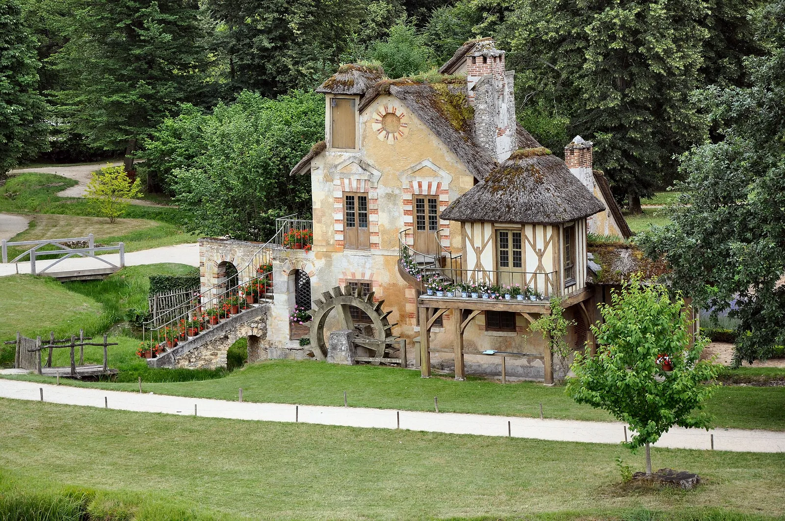 โรงสีของ Hameau de la Reine อาคารโครงไม้ หลังคามุงฟาง และกังหันน้ำ