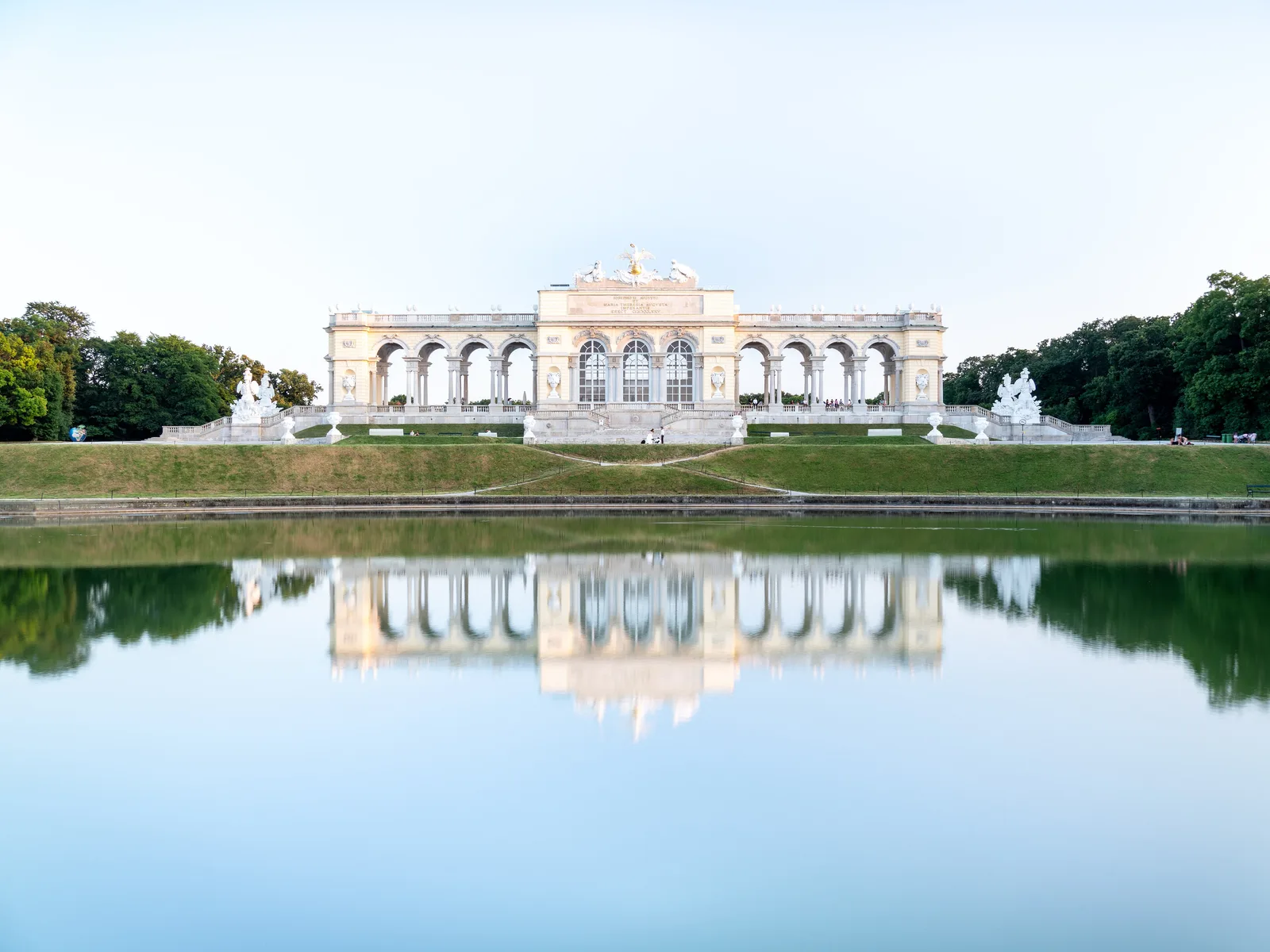 Gloriette บนเนินเหนือสวนของพระราชวังเชินบรุนน์ สะท้อนในสระน้ำ ภาพถ่ายเมื่อ 25 มิถุนายน 2019