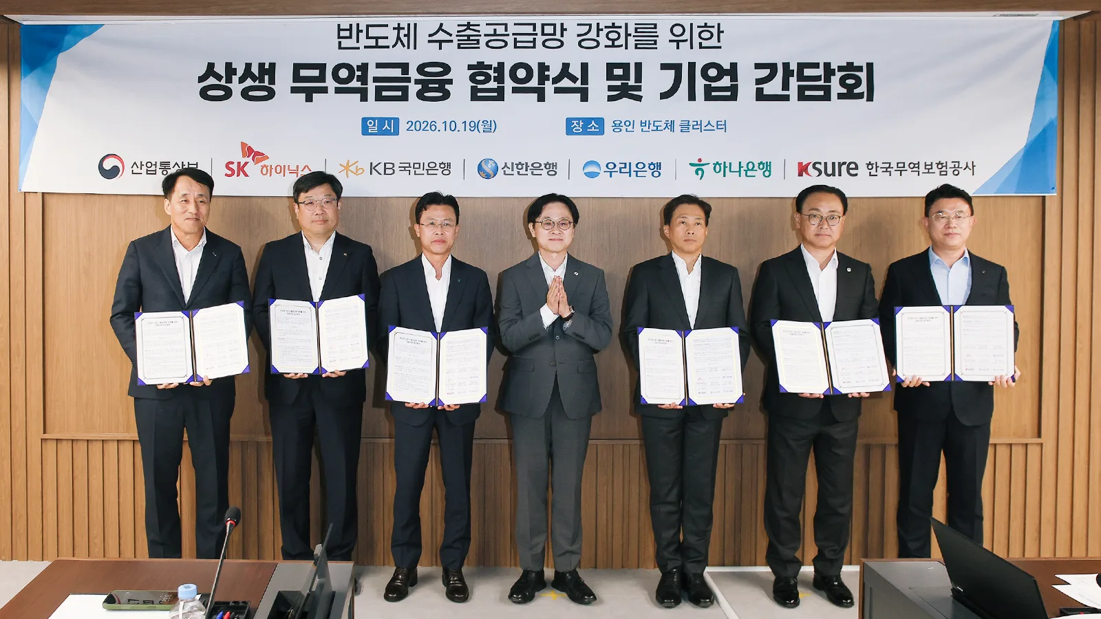 ผู้แทนกระทรวง SK hynix ธนาคาร KB Kookmin, Shinhan, Woori, Hana และ K-SURE ถือเอกสารข้อตกลงค้ำประกันสินเชื่อเพื่อห่วงโซ่อุปทานส่งออกเซมิคอนดักเตอร์ ที่คลัสเตอร์ยงอิน 19 ตุลาคม 2026