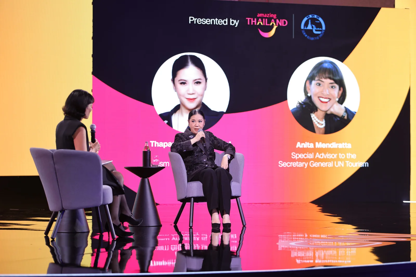 เวทีสนทนาในงาน CNN Global Perspectives: In Bangkok ที่ ททท. เป็นพาร์ตเนอร์ จอด้านหลังแสดงภาพผู้ว่าการ ททท. และที่ปรึกษาพิเศษของเลขาธิการ UN Tourism