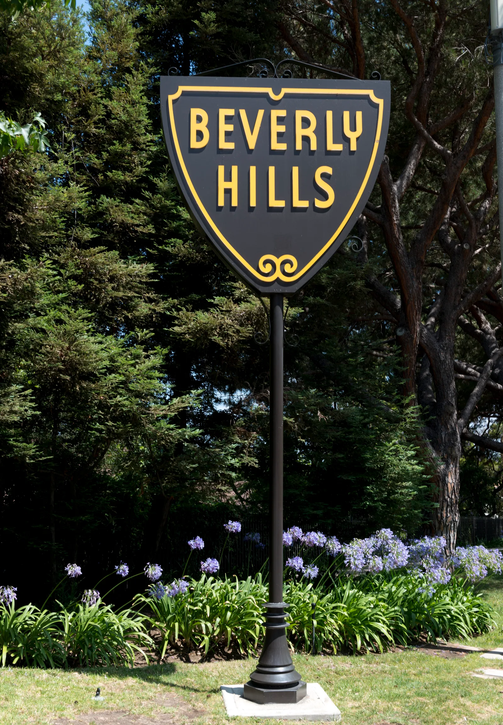 ป้ายชื่อเมือง Beverly Hills ทรงโล่สีดำขอบทองกลางสวนดอกไม้ เดือนกรกฎาคม 2012