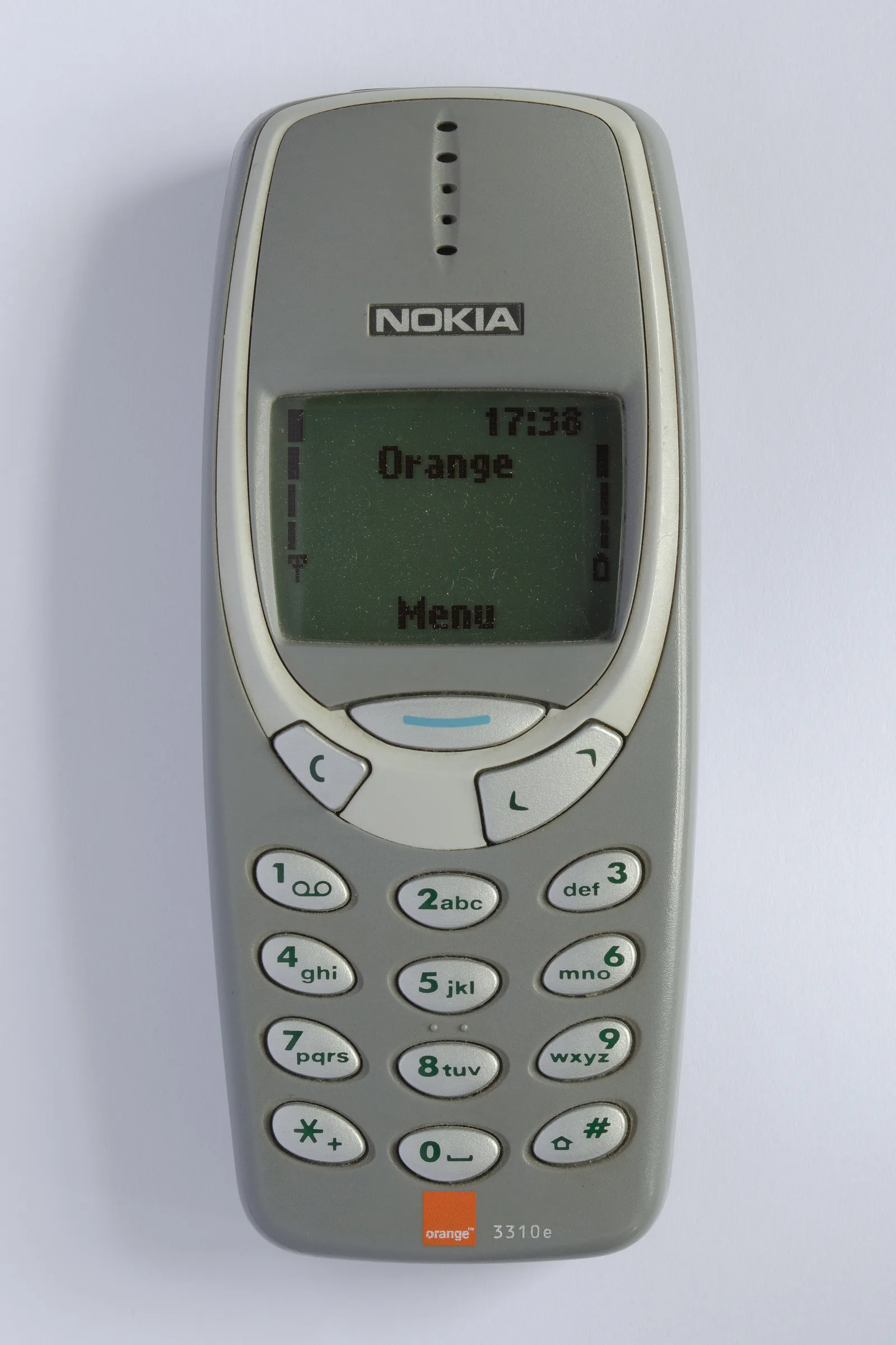 ด้านหน้าของมือถือ Nokia 3310 สีเทาที่มีตรา Orange และรหัสรุ่น 3310e หน้าจอแสดงคำว่า Orange