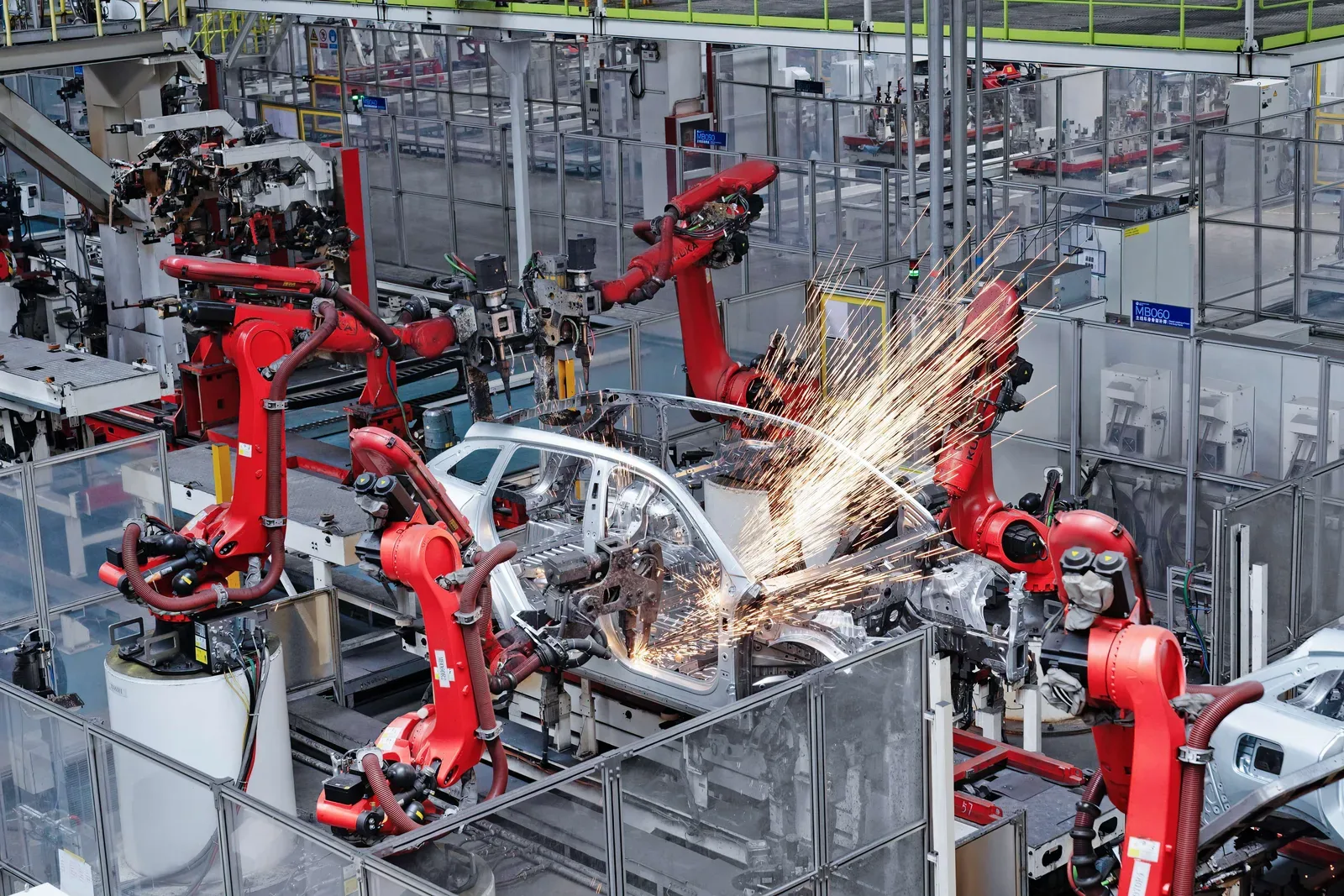 หุ่นยนต์สีแดงกำลังเชื่อมตัวถังรถในโรงงาน Leapmotor มีประกายไฟจากการเชื่อม