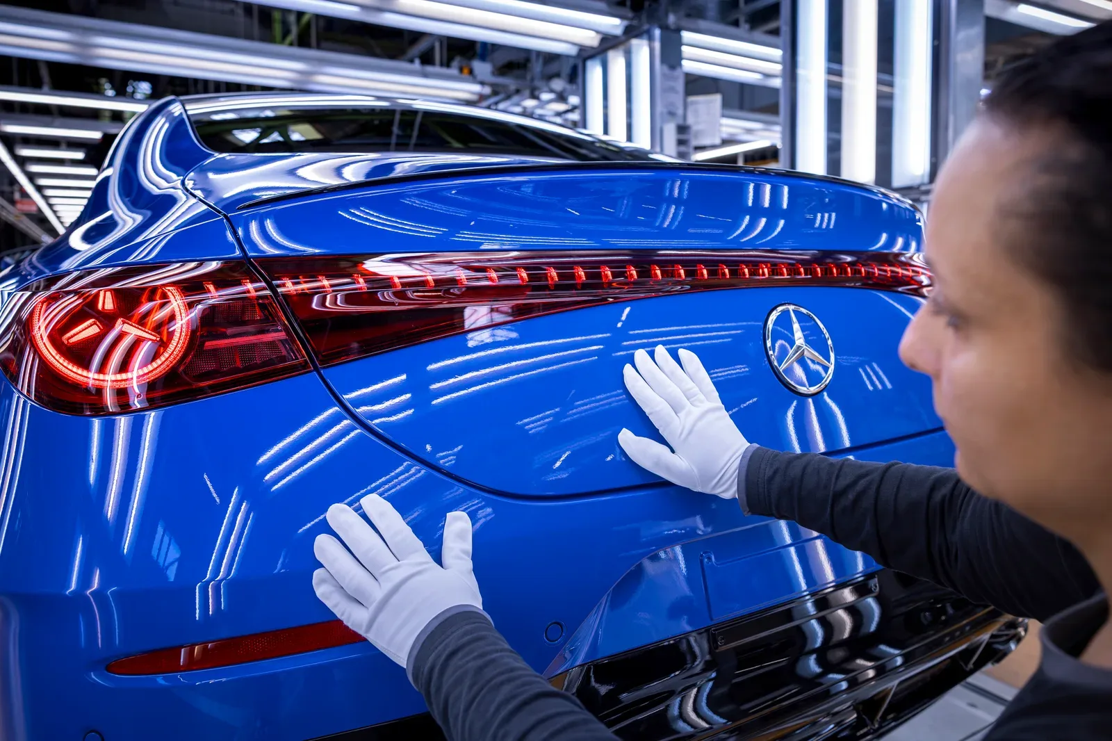 พนักงานสวมถุงมือขาวตรวจท้ายรถ CLA สีน้ำเงินบนสายการผลิตของโรงงาน Rastatt ประเทศเยอรมนี