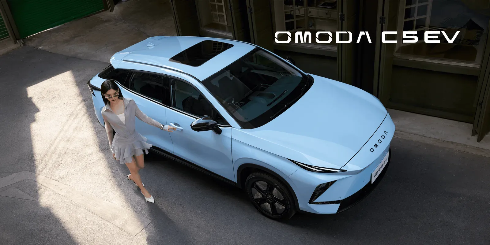 OMODA C5 EV สีฟ้าอ่อน มุมมองจากด้านบน มีผู้หญิงยืนข้างรถ