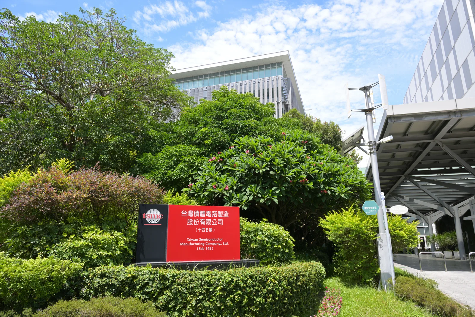 ป้ายชื่อ Taiwan Semiconductor Manufacturing Company (Fab 14B) หน้าโรงงาน Fab 14B ของ TSMC ในอุทยานวิทยาศาสตร์ไต้หวันตอนใต้ เมืองไถหนาน ถ่ายเมื่อพฤษภาคม 2025