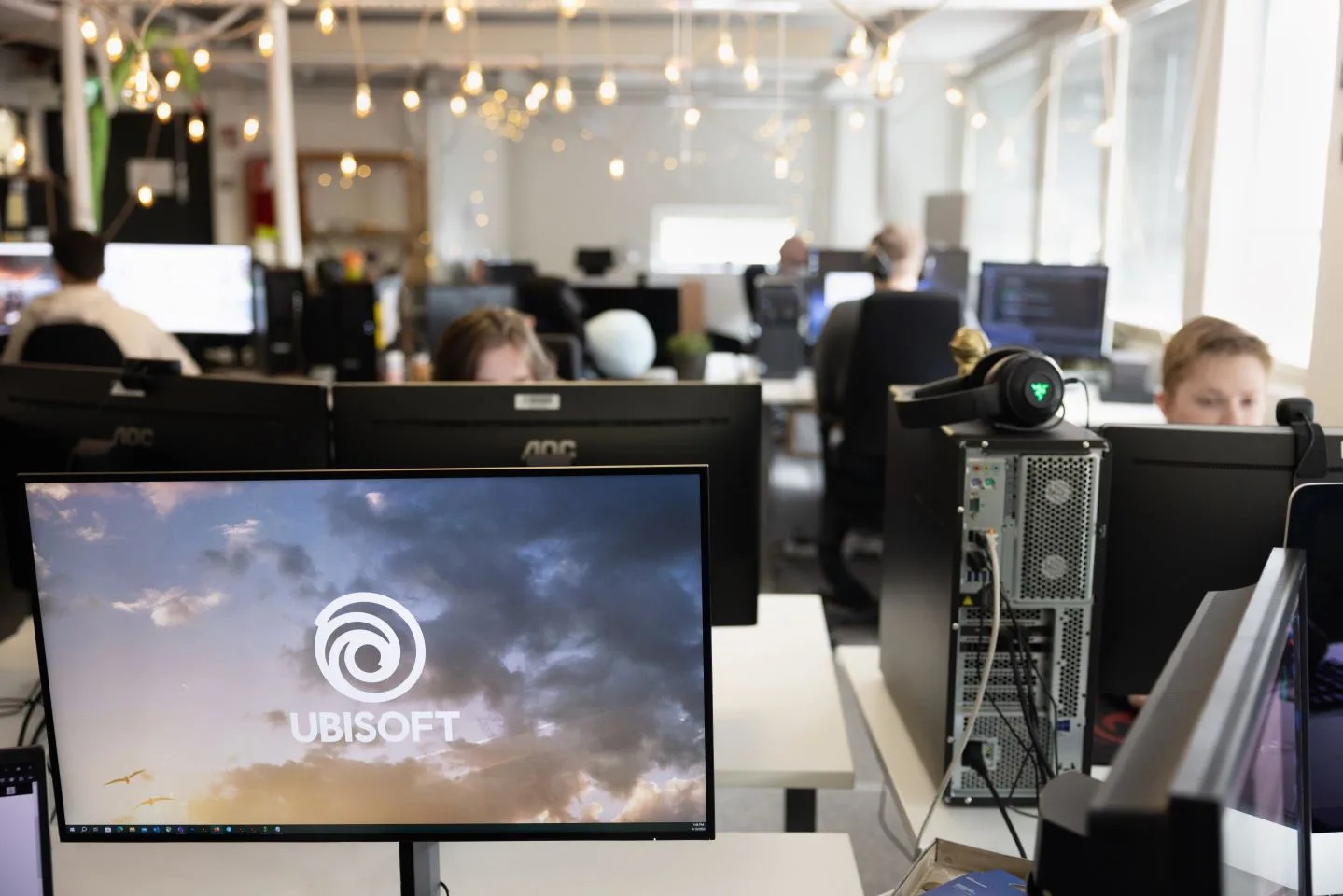 บรรยากาศการทำงานในสตูดิโอ Ubisoft RedLynx ที่ถูกเสนอปิด มีจอคอมพิวเตอร์แสดงโลโก้ Ubisoft บนโต๊ะทำงาน ภาพจากเว็บไซต์ของ RedLynx
