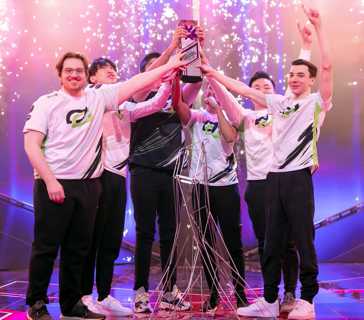 ผู้เล่น OpTic Gaming ในเสื้อทีมสีขาวลายเขียวดำ กางเกงดำ และรองเท้าผ้าใบ ชูถ้วยแชมป์ VALORANT Masters Reykjavík 2022 บนเวที