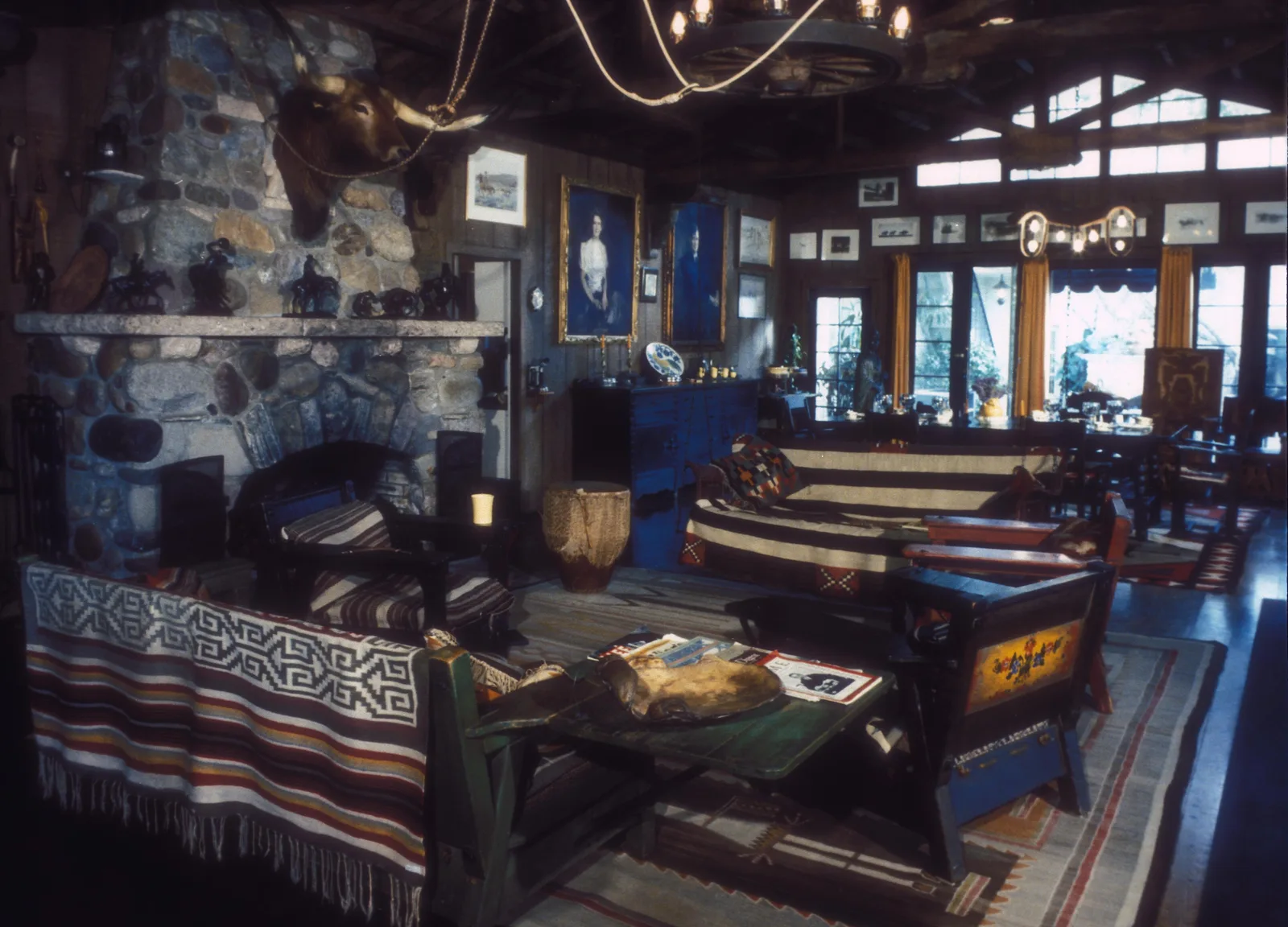 ห้องนั่งเล่นในบ้านไร่ของ Will Rogers เพดานโครงไม้ เตาผิงหิน ผ้าทอลายพื้นเมืองบนโซฟา และของสะสมแบบตะวันตกบนผนัง ก่อนไฟป่าปี 2025
