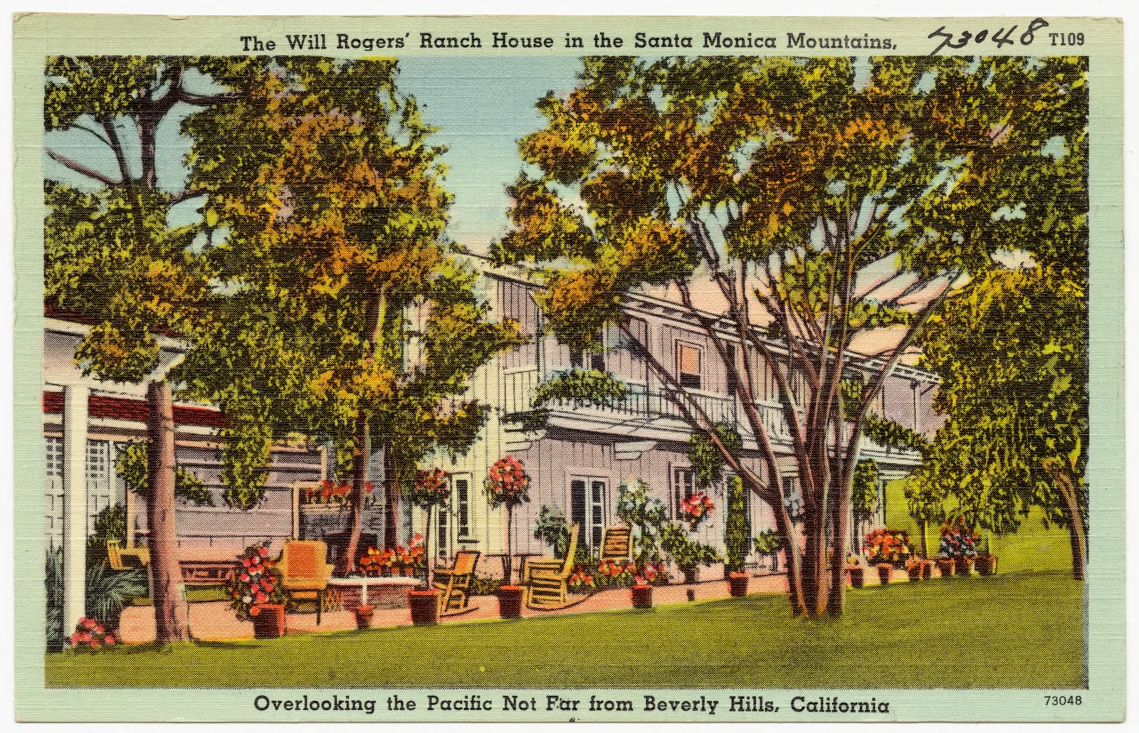 โปสการ์ดภาพสีของ Tichnor Brothers ยุคราว 1930–1945 แสดงลานหน้าบ้านไร่ของ Will Rogers มีเก้าอี้ ไม้ดอกในกระถาง และต้นไม้ใหญ่
