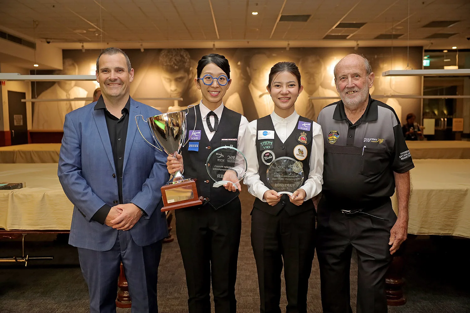 Onyee Ng ถือถ้วยแชมป์และ Mink Nutcharut ถือโล่รองแชมป์สนุกเกอร์หญิง Australian Women's Open 2026 ยืนร่วมกับเจ้าหน้าที่สองคนที่ Mounties ซิดนีย์