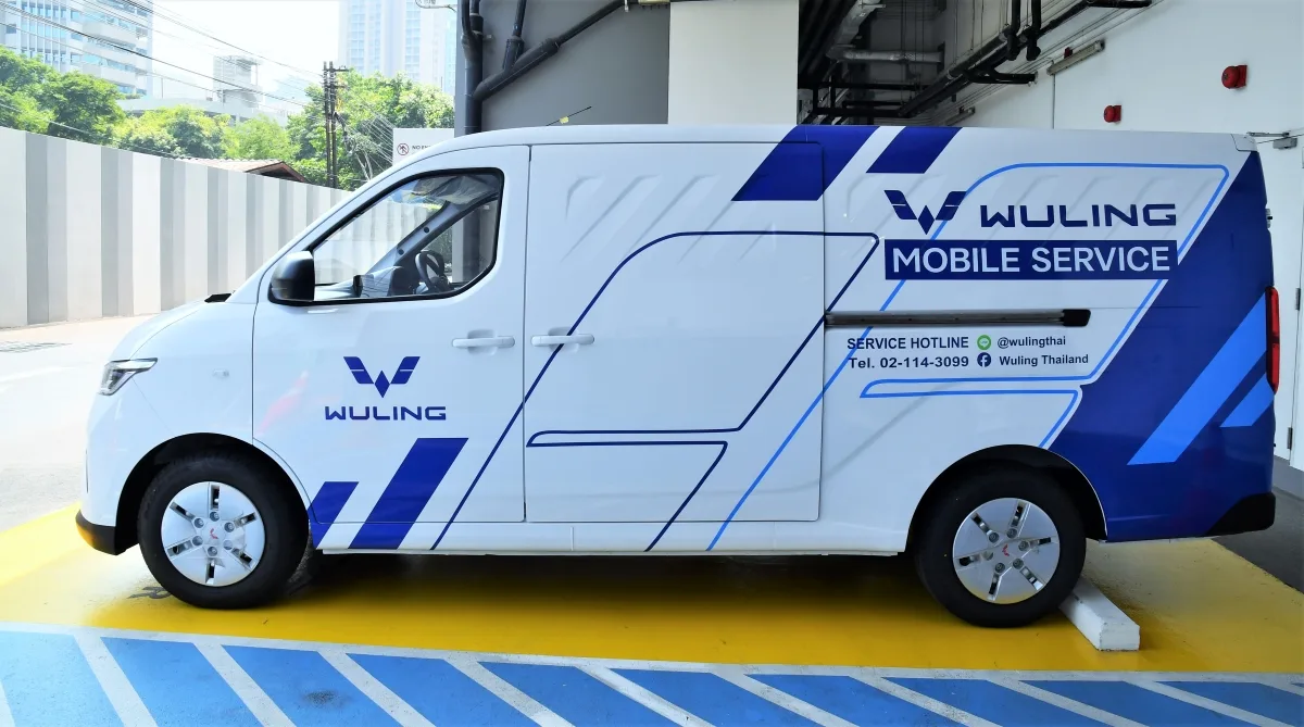 รถตู้ไฟฟ้าสีขาวลายน้ำเงินติดข้อความ Wuling Mobile Service พร้อมหมายเลขสายด่วนบริการ