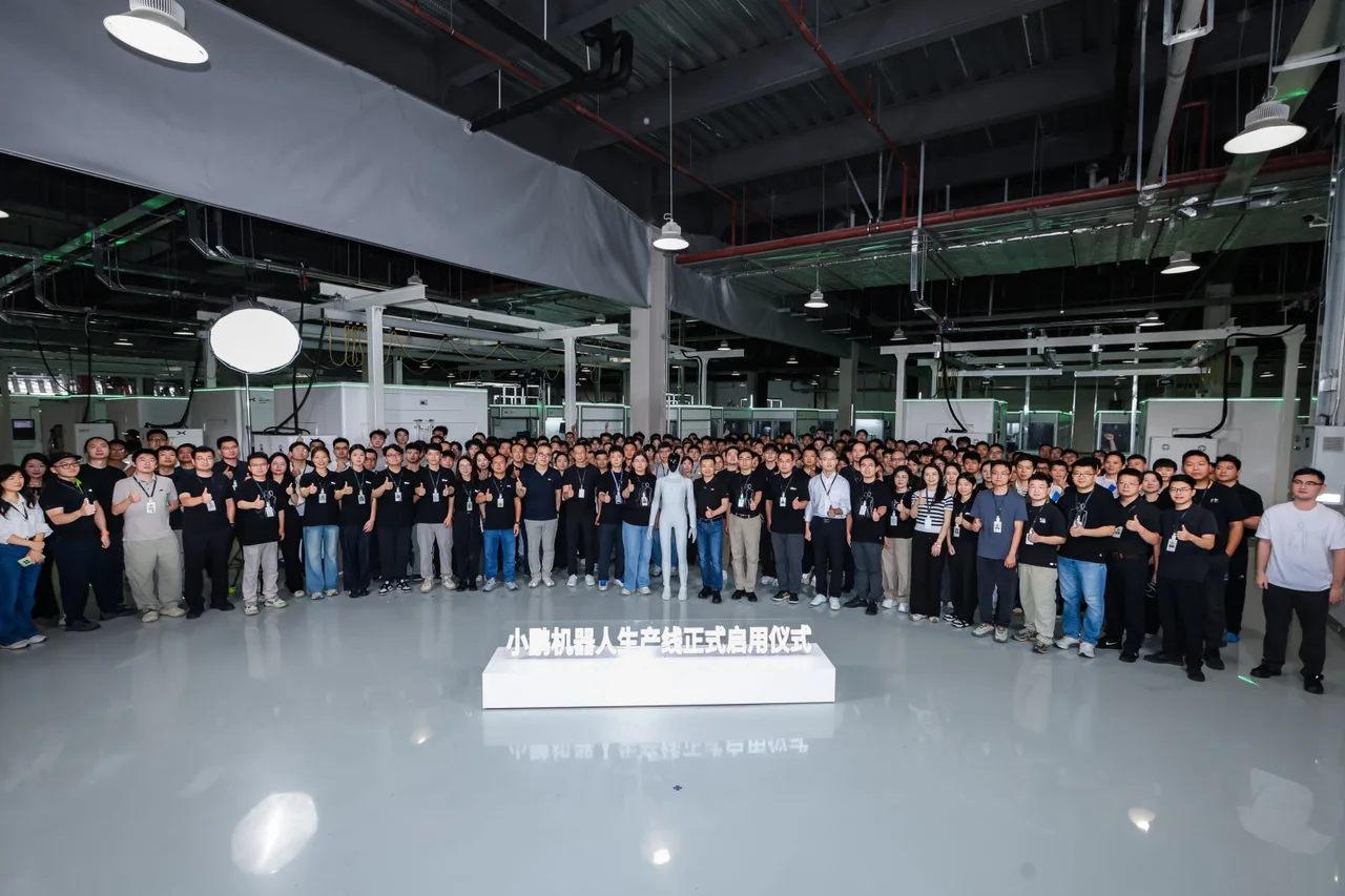 พนักงาน XPENG จำนวนมากยืนรวมกันในโรงงานระหว่างพิธีเปิดสายการผลิตหุ่นยนต์ฮิวแมนนอยด์