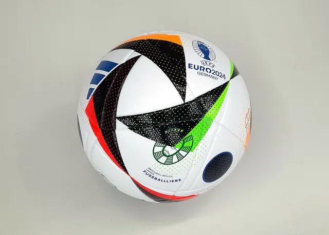 ลูกฟุตบอลแข่งขัน UEFA Euro 2024 ลาย Fussballliebe สีขาวดำตัดสีสดใส วางบนพื้นหลังสีเรียบ