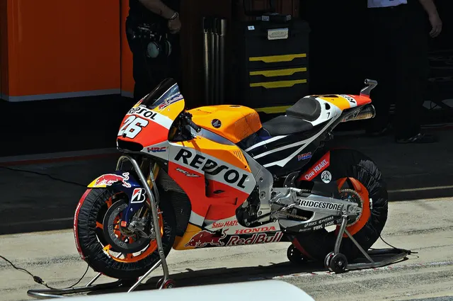 มอเตอร์ไซค์แข่ง Honda RC213V สีส้มขาวบนขาตั้งในพิทเลน ยางสลิกและแฟริ่งเต็มคัน ฤดูกาล 2015
